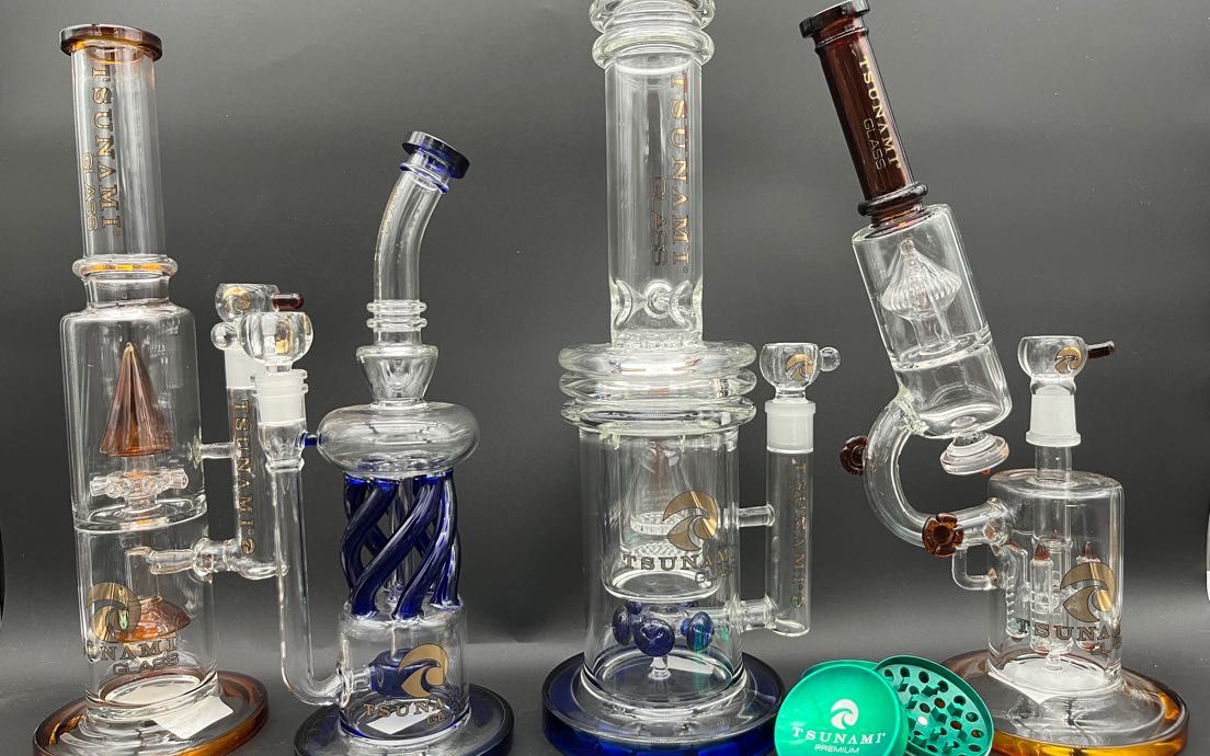Five glass water pipes and dab rigs of different shapes standing side by side.