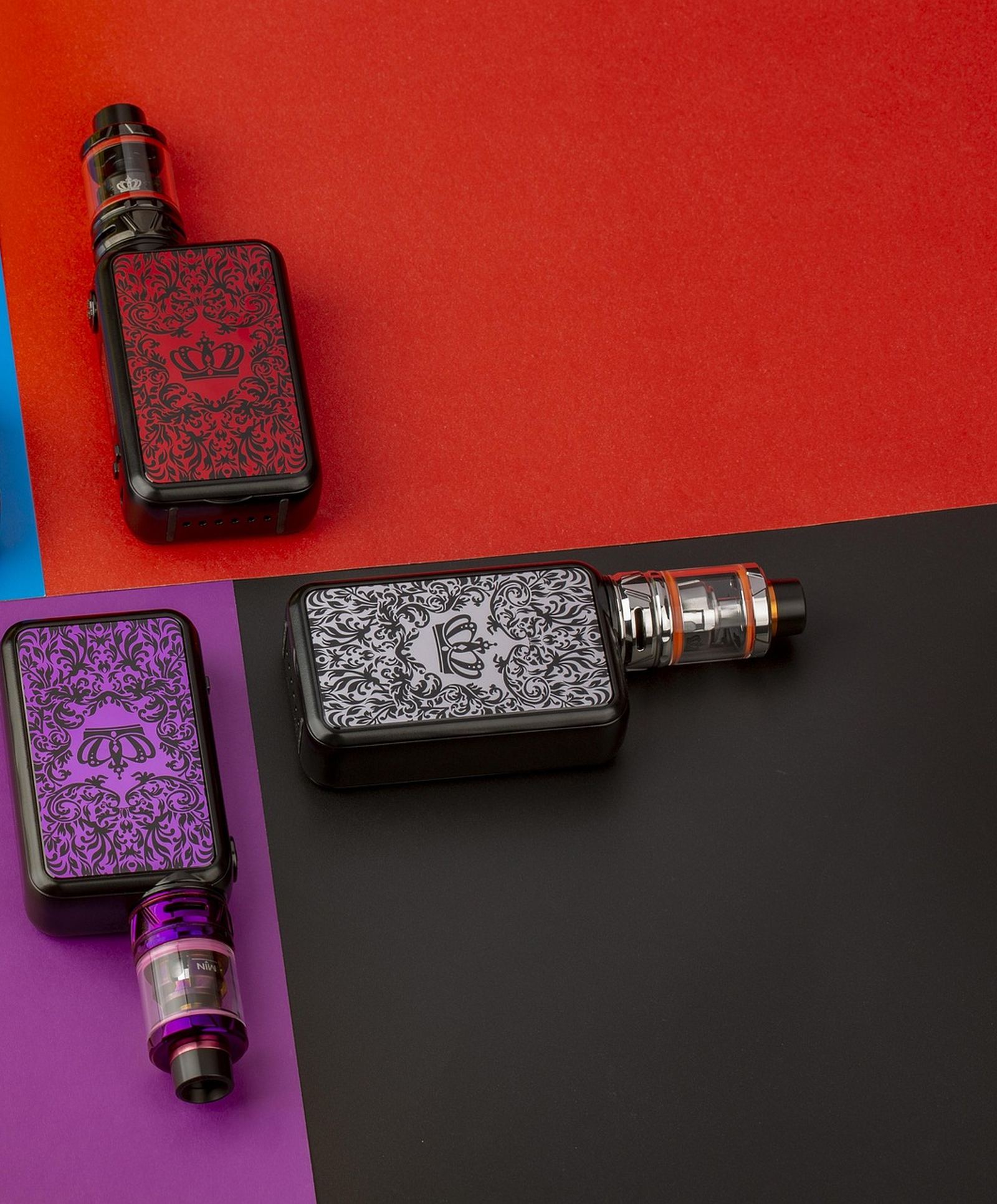 Vape devices and tanks laid out on blocks of red, purple and black colour.