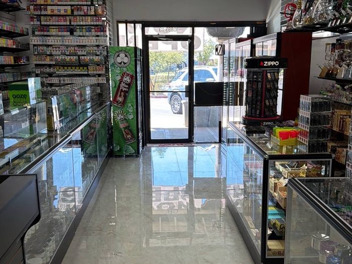 The shop floor looking toward the front door, with the wall of e-liquid and disposables on the left and glass cases on both sides.